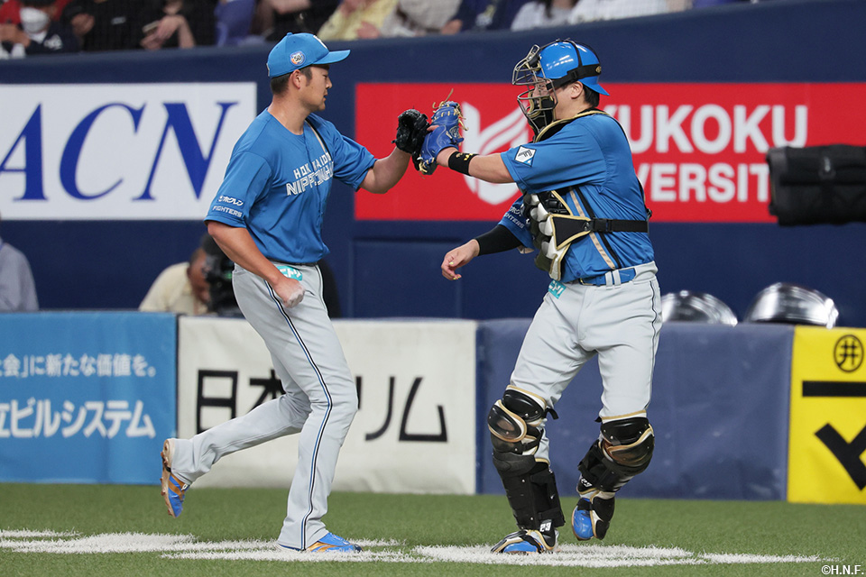 8回裏を三者凡退に抑えた齋藤友投手と伏見選手