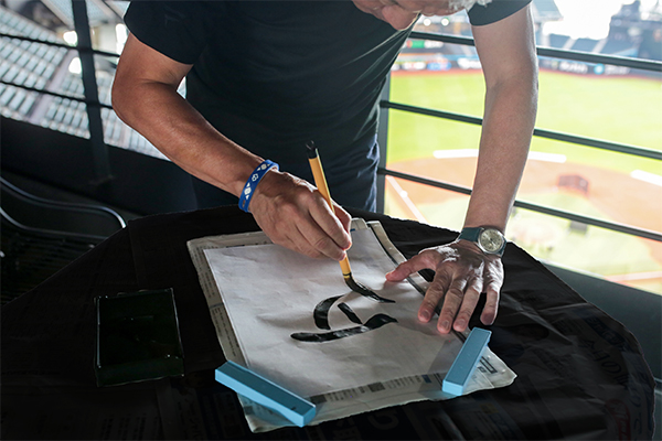 文字を書く小村勝球団社長